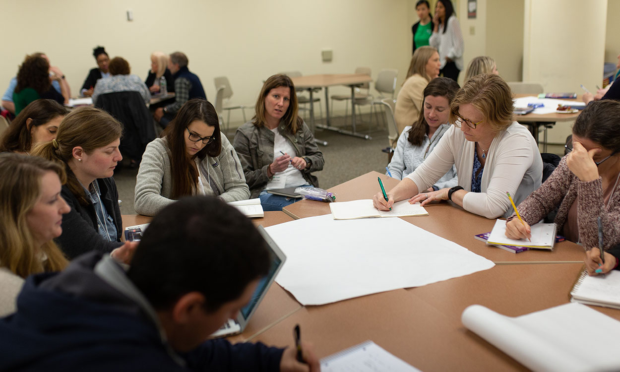 Educators sitting at table and working together at a professional development training.