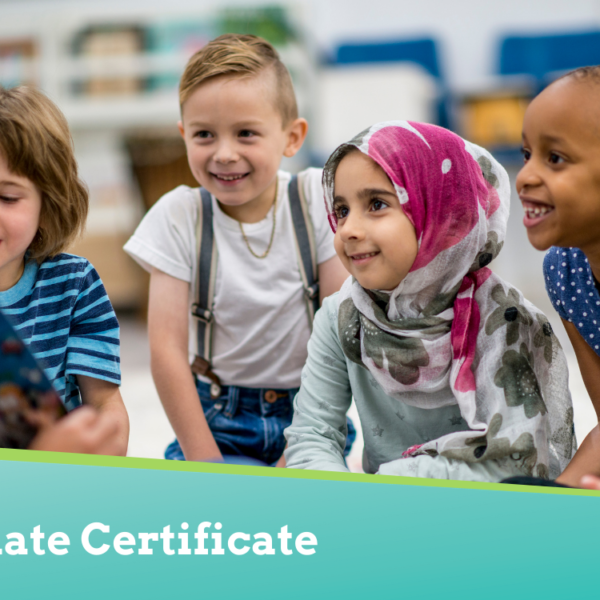 Teacher sitting in front of classroom of students, showing and reading a book to the group.