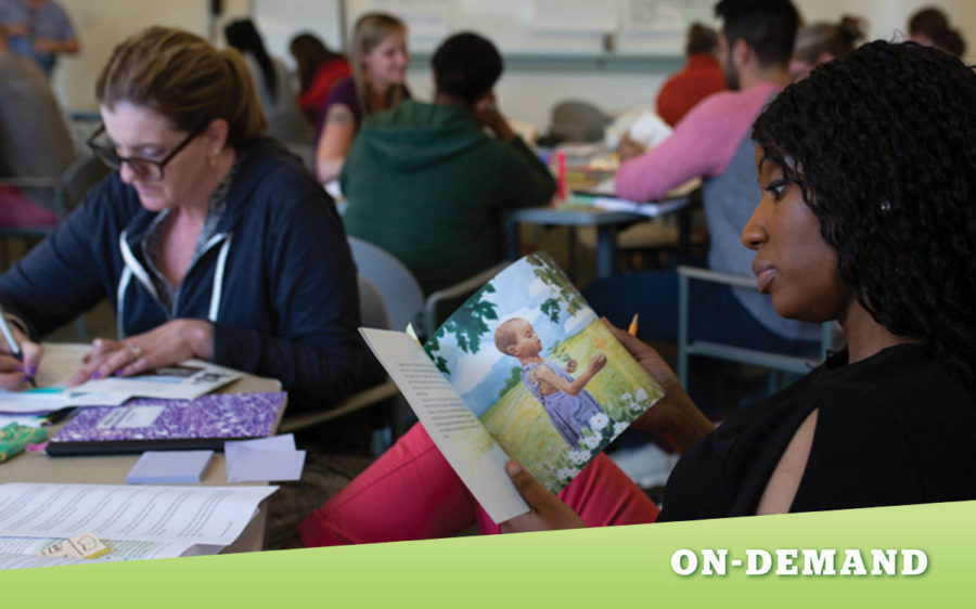 Educator sitting a table, looking through a children's book.