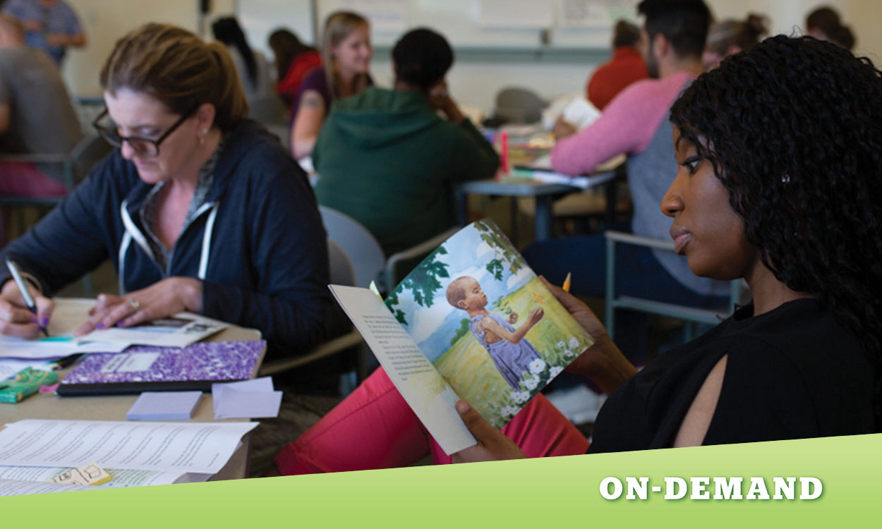 Educator sitting a table, looking through a children's book.