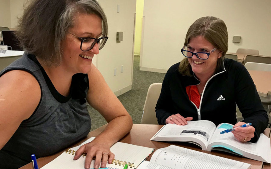 Two smiling educators sitting at a table together.