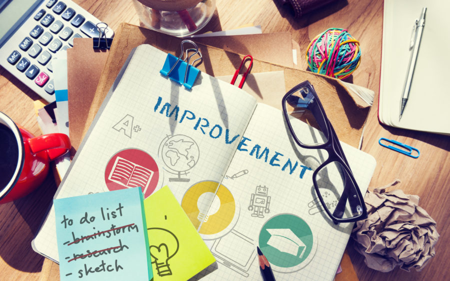 Image of a desk with a notebook open that reads "improvement"